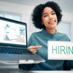Woman, pointing and hiring sign, laptop and human resources with offer, recruitment and job opportu